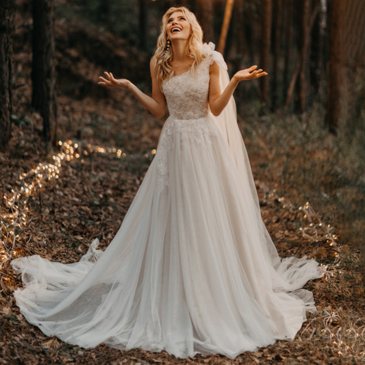 One-shoulder boho wedding gown: ruched bow, lace & tulle, A-line, built-in bra, sweep train.